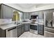 Modern kitchen features stainless steel appliances, light countertops, gray cabinets and updated fixtures at 1011 Dundee Cir, Leesburg, FL 34788