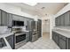 Modern kitchen with gray cabinets, stainless steel appliances, and tile flooring at 1011 Dundee Cir, Leesburg, FL 34788