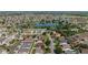 Overhead view of a dense residential area featuring a scenic pond, mature trees, and houses with pristine landscaping at 1014 Nash Loop, The Villages, FL 32162