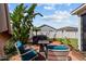 Backyard patio area features a hot tub, chairs, fire pit, and is surrounded by tropical plants and a privacy fence at 1014 Nash Loop, The Villages, FL 32162