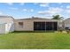 Wide view of the backyard showing the screen lanai, patio with hot tub, and large well-kept lawn at 1014 Nash Loop, The Villages, FL 32162