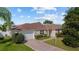 Charming home exterior with a well-manicured lawn, mature landscaping, and a brick driveway at 1014 Nash Loop, The Villages, FL 32162