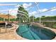A relaxing screened-in pool with a waterfall feature and patio seating, surrounded by lush landscaping at 1175 Johnston Path, The Villages, FL 32162