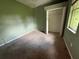A bedroom with green walls and carpeted flooring, features a closet with shelving and a window at 1209 Cathcart Cir, Sanford, FL 32771