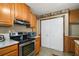 Cozy kitchen featuring wood cabinets, black appliances, and white bi-fold pantry doors at 124A Shady Ln, Eustis, FL 32726