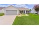 Lovely home exterior with an attached garage, surrounded by a lush green lawn and manicured landscaping at 1313 Arredondo Dr, The Villages, FL 32162