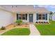 Charming home exterior showcasing a blue front door, meticulous landscaping, and well-maintained lawn at 1313 Arredondo Dr, The Villages, FL 32162