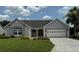 Lovely single-story home featuring a well-manicured lawn, flower beds, and a two-car garage at 1512 Nueva Pl, The Villages, FL 32159
