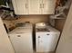 A laundry room features a washer and dryer with overhead cabinets for optimal storage and convenience at 1512 Nueva Pl, The Villages, FL 32159