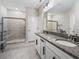 Bright bathroom featuring a double vanity with granite countertops and a tiled shower at 17108 Se 111Th Terrace Rd, Summerfield, FL 34491