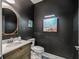 Stylish powder room featuring black walls, decorative mirror, and coastal artwork creating a serene ambiance at 17108 Se 111Th Terrace Rd, Summerfield, FL 34491