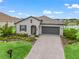 Inviting exterior view featuring a well-manicured lawn, brick driveway, and gray facade at 17108 Se 111Th Terrace Rd, Summerfield, FL 34491