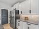 Stylish kitchen area boasts stainless steel refrigerator, white cabinetry, granite countertops, and convenient access to pantry at 17108 Se 111Th Terrace Rd, Summerfield, FL 34491