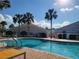 Beautiful pool area with inviting blue water surrounded by palm trees, lounge chairs, and community buildings at 17108 Se 111Th Terrace Rd, Summerfield, FL 34491