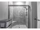 Walk-in shower with gray tile surround, built-in bench, and glass door at 17108 Se 111Th Terrace Rd, Summerfield, FL 34491