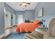 Comfortable bedroom with an orange quilt, a ceiling fan, and a relaxing seating area at 17406 Chateau Pine Way, Clermont, FL 34711