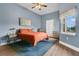 Cozy bedroom with blue walls, a ceiling fan, wood floors, and an orange quilt on the bed at 17406 Chateau Pine Way, Clermont, FL 34711