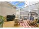 Relaxing screened patio with comfortable seating, a modern egg chair, and an outdoor grill at 17406 Chateau Pine Way, Clermont, FL 34711