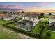 Stunning aerial view of a lakeside home with a screened pool, green lawn, and sunset sky at 17700 Sawgrass Run, Tavares, FL 32778
