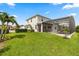 Expansive backyard with manicured lawn, screened-in pool, and view of the beautiful greenery at 17700 Sawgrass Run, Tavares, FL 32778