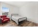 Cozy bedroom with wood-look floors, a metal bed frame, and a red chair by the window at 17700 Sawgrass Run, Tavares, FL 32778