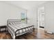 Bright bedroom featuring a checked bedspread, a side table, and an open bathroom doorway at 17700 Sawgrass Run, Tavares, FL 32778