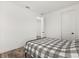 Simple bedroom featuring a plaid bedspread, a white wall, and wood-look flooring at 17700 Sawgrass Run, Tavares, FL 32778