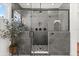 Modern shower with gray tile, glass enclosure, rain shower head, and a decorative plant, creating a spa-like experience at 17700 Sawgrass Run, Tavares, FL 32778