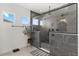 Stylish bathroom showcasing a glass-enclosed shower with modern fixtures, gray tiling, and natural light at 17700 Sawgrass Run, Tavares, FL 32778