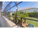 View of the landscaped backyard and screened-in lanai with travertine flooring and outdoor lighting fixtures at 2077 Vickers Pl, The Villages, FL 32163