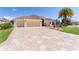 Front exterior of a single-story home with a three-car garage, tile roof and meticulously landscaped yard at 2077 Vickers Pl, The Villages, FL 32163