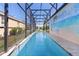 Long, clear and screened-in pool with travertine tile decking and views of the house and a mural at 2077 Vickers Pl, The Villages, FL 32163