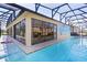 Screened-in pool area featuring a long pool, tiled deck, and a painted mural wall with sliding glass doors leading to the house at 2077 Vickers Pl, The Villages, FL 32163