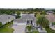 Aerial view of a single-story home with a paver driveway, well-manicured lawn, and scenic lake view at 2082 Vision Ct, The Villages, FL 32163