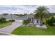 Beautifully landscaped home with mature palm trees, an American flag and a three-car garage at 2082 Vision Ct, The Villages, FL 32163