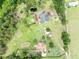 Aerial view of a home and property with green lawns, scattered trees, outbuildings and a pond at 21320 Paradise Way, Eustis, FL 32736