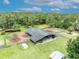 Aerial shot of large barn surrounded by paddocks and grazing land, with a backdrop of mature trees at 21320 Paradise Way, Eustis, FL 32736