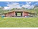 Large barn exterior showing open stalls, green grass, landscaping, and farm equipment at 21320 Paradise Way, Eustis, FL 32736
