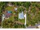 An aerial view shows the home's layout with a long drive, lush yard, pool nearby and a private, wooded setting at 2163 County Road 243F, Wildwood, FL 34785