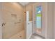 Modern walk-in shower features beige tile, a built-in shelf, and a glass door leading to the outdoors at 2163 County Road 243F, Wildwood, FL 34785