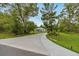 Long paved driveway leading to a charming house surrounded by lush trees and landscaping at 2163 County Road 243F, Wildwood, FL 34785