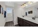 Bathroom with dark wood cabinets, double sink, and a glass-door shower at 2532 Autumn Stream Dr, Leesburg, FL 34748
