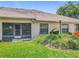 Back exterior with sliding glass door and lush green lawn and garden at 264 Juniper Way, Tavares, FL 32778