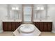 This primary bath features a soaking tub, dual sinks, and large mirrors over dark wood cabinets at 313 Blue Cypress Dr, Groveland, FL 34736
