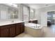 This bright bathroom features a soaking tub and dual sinks with dark wood cabinets and quartz countertops at 313 Blue Cypress Dr, Groveland, FL 34736