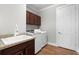 Well-lit laundry room with modern washer and dryer, brown cabinets and wood-look floors at 313 Blue Cypress Dr, Groveland, FL 34736