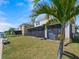 Spacious backyard with lush grass, a screened-in patio, and views of neighboring homes and community features at 395 Blue Cypress Dr, Groveland, FL 34736