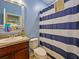 Bathroom features a vanity, toilet, mirror, and shower/tub with striped curtain at 395 Blue Cypress Dr, Groveland, FL 34736