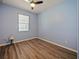 Empty bedroom with light blue walls, wood floors, and a bright window, ready for customization at 395 Blue Cypress Dr, Groveland, FL 34736