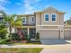 Two-story home boasts an attached two-car garage, manicured landscaping, and a charming front porch at 395 Blue Cypress Dr, Groveland, FL 34736